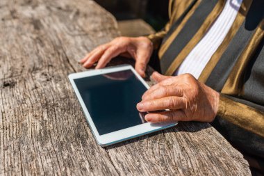 Elinde tablet olan yaşlı kadının elleri sıcak yaz gününde dışarıda. Odaklan..