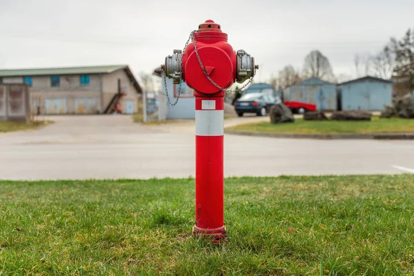 Jeden Červený Požární Hydrant Zeleném Trávníku Pozadí Několik Starých Garáží — Stock fotografie