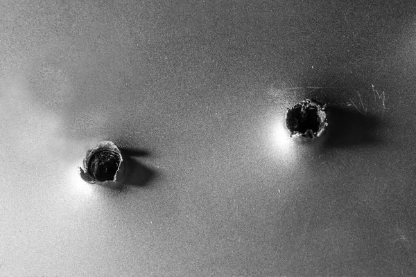 Two bullet holes in silver metal.Selective focus,closeup,copy space.