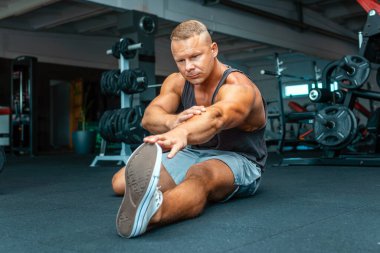 Kafkas sporcusu spor salonunda ısınıyor ve bacaklarını esnetiyor. Yaklaş..