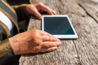 Elinde tablet olan yaşlı kadının elleri sıcak yaz gününde dışarıda. Odaklan..