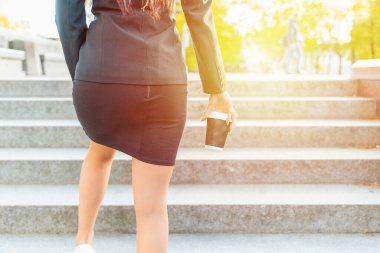 İş kadını yürüyor, merdivenlerde elinde kağıt kahve fincanıyla dikiz aynasıyla tırmanıyor. Beyaz iş kadını kısa etek giyiyor ve gün batımı şehrine gidiyor..