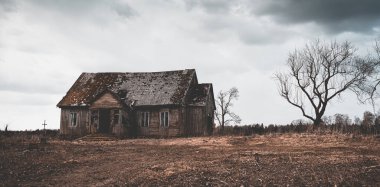 Eski ahşap ev, gece dramatik bulutlar. Terk Edilmiş Korku Evi. Geceleri yakınlarda bir ağaç var. Bayrak, panoramik manzara..