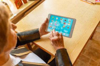 Üst düzey kadın internet üzerinden uygulama kullanarak alışveriş yapıyor, evinde oturuyor. Tablet bilgisayarlı yaşlı kadın. Seçici odaklanma. Yakın plan. Telsiai, Litvanya 05-08-2022.