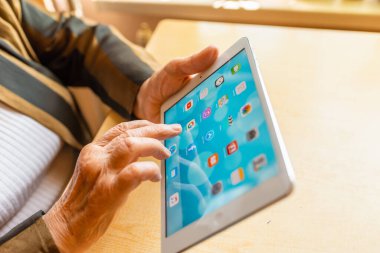 Üst düzey kadın internet üzerinden uygulama kullanarak alışveriş yapıyor, evinde oturuyor. Tablet bilgisayarlı yaşlı kadın. Seçici odaklanma. Yakın plan. Telsiai, Litvanya 05-08-2022.