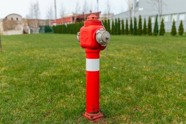 Yeşil çimenlikte tek bir kırmızı yangın musluğu, fabrikanın yanında. Sonbahar, ilkbahar, yaz günü. Uzayı kopyala..