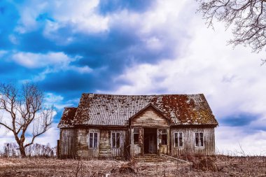 One old abandoned horror wooden house,dramatic stormy clouds with trees at autumn evening.Nice background.