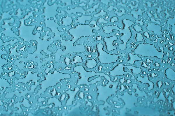 Water drops condensate on blue background texture on transparent glass. backdrop glass covered with abstract drops of water.Selective focus.