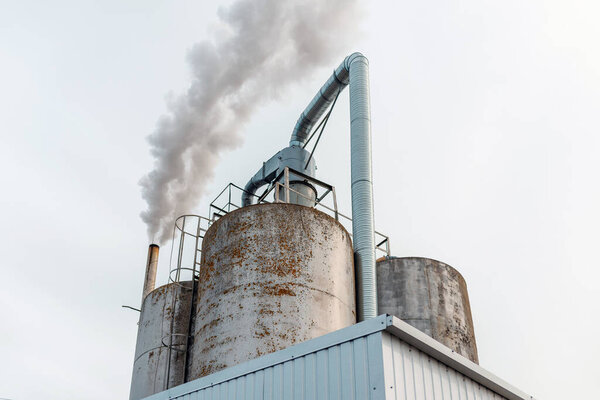 Chemical factory,smoke stack,CO2 greenhouse gas emissions coming from the smoking chimney pipe.Cloudy blue sky background.Copy space.