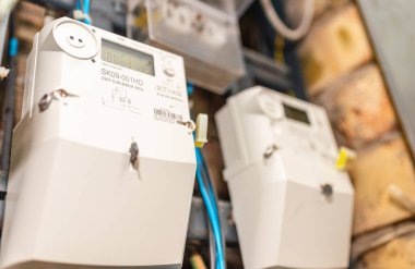 İki akıllı elektrik sayacı güç kullanımını ölçüyor. Modern akıllı şebeke yerleşim yeri dijital güç sayacına yakın plan. Kapalı alanda çekim..