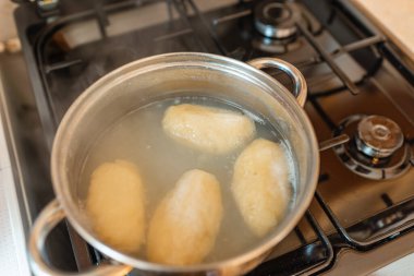 Geleneksel Litvanya patatesli börekleri tencere suyunda. Hamur köfteleri rendelenmiş ve doğranmış patateslerden yapılıyor..