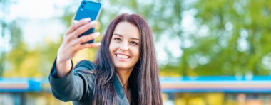 Young smiling pretty beautiful business woman making selfie photo at the street summer evening.Banner,advertisement.
