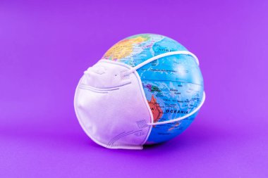 Dünya Gezegeni, yüz maskeli, düz bir şekilde mor zeminde yatıyordu. Dünya tıbbi konsepti..