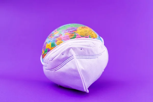 World Planet Earth with face mask protect flat lay on the purple ,veri peri background.World medical concept.