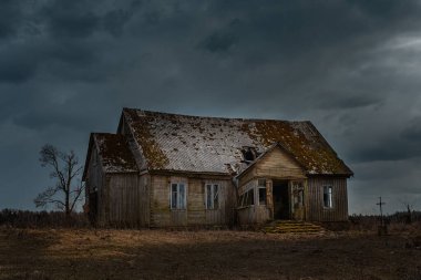 Eski ahşap ev, gece dramatik bulutlar. Terk Edilmiş Korku Evi. Geceleri tek bir ağaç var. Tonlanmış..