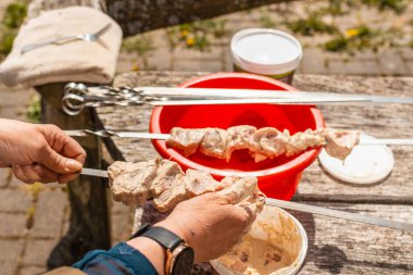 Kadın eli alüminyum metal havzadan tükürüğe çiğ domuz eti sokuyor, açık havada poultru shashlik pişiriyor. yaz güzel gün.