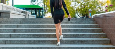 Kariyer kavramı. Merdivenlerdeki genç iş kadınının arka planı. Elinde kağıt bardak, kırpılmış bir bakış açısı olan iş kadını..