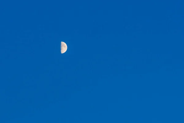 Small moon over blue sky glowing background.The Moon illuminated by the Sun.