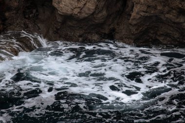 Okyanus dalgası arka planı deniz suyunu kırıyor kayalık kıyı dalgalı deniz turkuaz su gradyan köpüğü. Açık denizde büyük dalgalar. Yaz musonu. Bir deniz dalgasının beyaz tepesi.