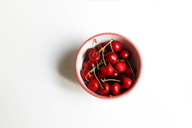 Sweet cherries in a  bowl on white table and light background.Bowl of fresh red cherries on white background