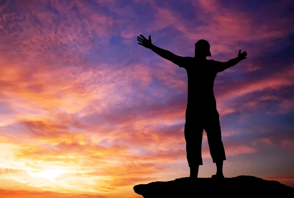 Silhouette eines Mannes auf einem Berggipfel auf feurig orangefarbenem Hintergrund — Stockfoto