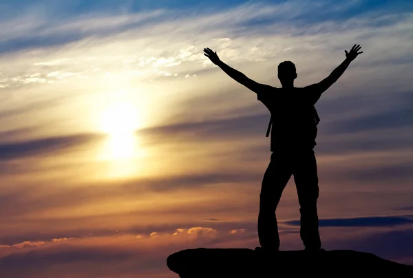 Silhouette d'un homme au sommet d'une montagne sur fond de coucher de soleil — Photo