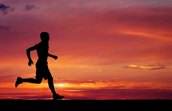 Silhouette dell'uomo che corre sullo sfondo ardente del tramonto Foto Stock