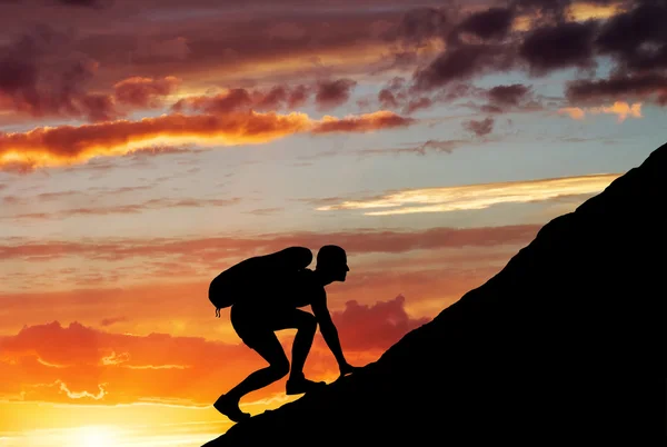 Silhouette of a man that climbs the mountain on sunset sky backg — Stock Photo, Image