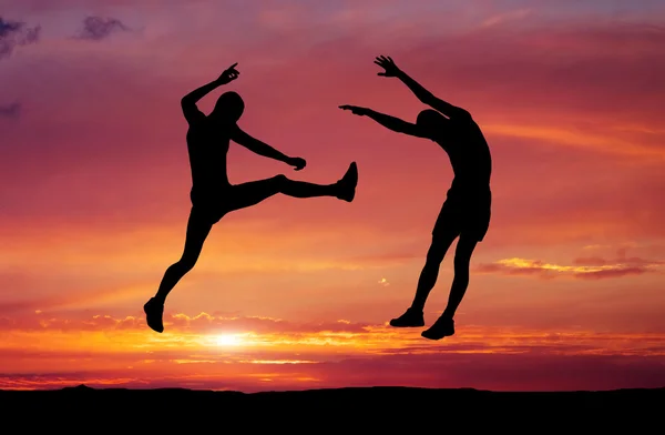Gün batımı ateşli zemin üzerine iki savaşçıları Silhouettes. — Stok fotoğraf