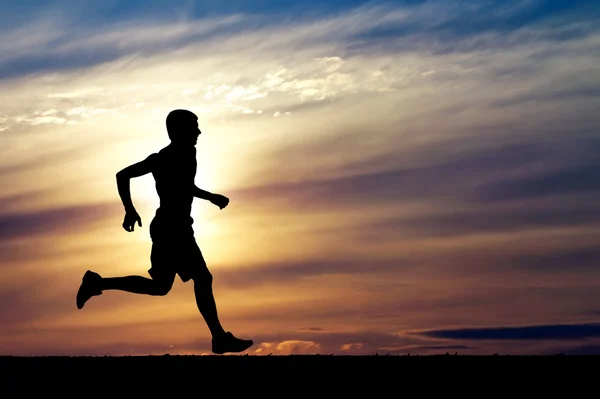 Silueta del hombre corriendo sobre el fondo del atardecer — Foto de Stock