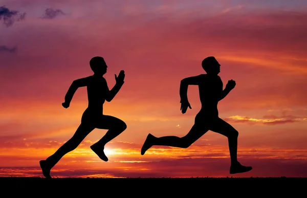 Silhouettes of two runners on sunset fiery background — Stock Photo, Image