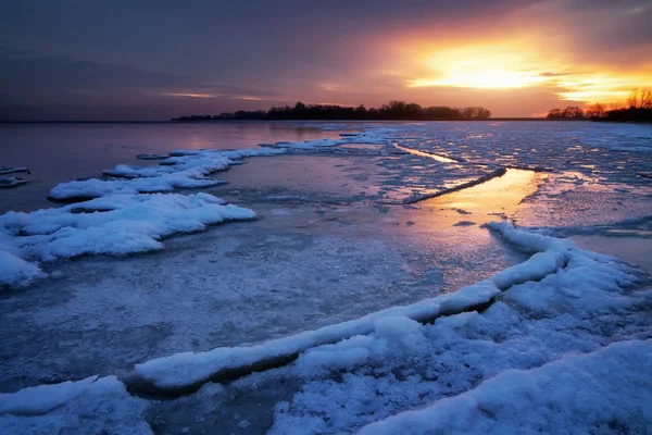 Zimowy krajobraz z zamarzniętym jeziorem i zachodem słońca niebo. — Zdjęcie stockowe