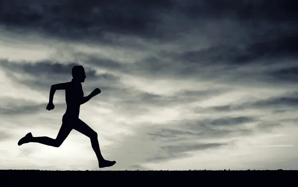 Silueta del hombre corriendo en el cielo nublado . — Foto de Stock