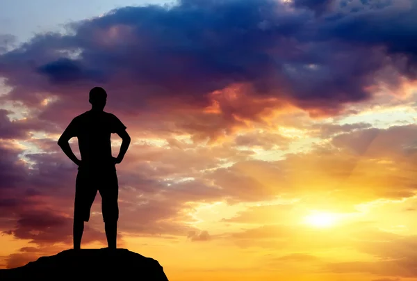 Silhueta de homem sobre pedra ao pôr-do-sol. Homem no topo da montanha. Con — Fotografia de Stock