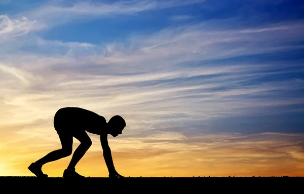 Silhouet van atleet in positie uit te voeren op zonsondergang achtergrond — Stockfoto