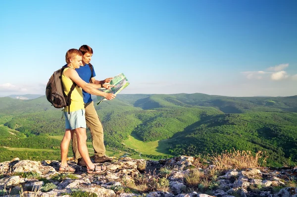 Two tourists in mountain read the map. Mans on top of mountain. — Stock Photo, Image