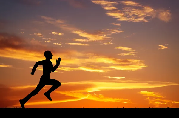 Silhouette of running man on sunset fiery background — Stock Photo, Image