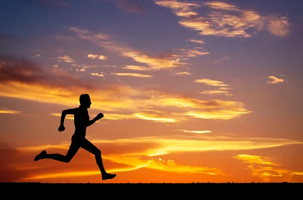 Silhouette of running man on sunset fiery background — Stock Photo, Image