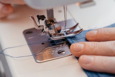 Kız efendi dikiş atölyesinde dikiş makinesine dikiş dikiyor..