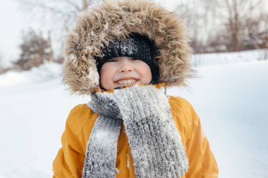Mutlu çocukluk. Turuncu ceketli ve kürklü bir çocuk gülümsüyor. Kameraya bakıyorum..
