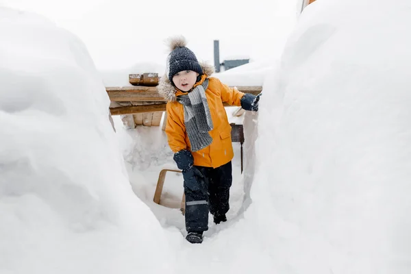 Representación de un niño feliz de cinco a seis años jugando en una deriva de nieve en el invierno y posando para la cámara. Feliz infancia. — Foto de Stock