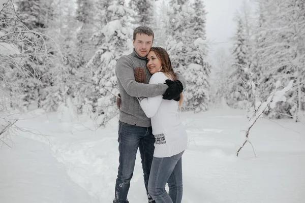 Una giovane coppia di hipster si abbraccia in un parco invernale. Vacanze invernali. Vacanze di Natale all'aperto nella foresta — Foto Stock