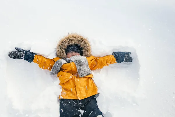 Happy boy est un enfant qui joue lors d'une promenade hivernale dans la nature. Un enfant fait un ange de neige. — Photo