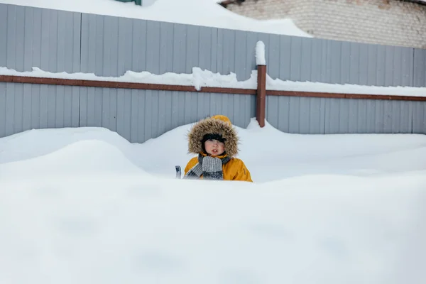 Menino bonito de cinco ou seis anos de idade está se divertindo jogando enquanto caminha no quintal na rua. Atividades ao ar livre de inverno para crianças. — Fotografia de Stock