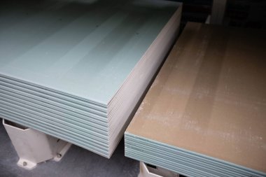 Farklı markalardan oluşan neme dayanıklı alçı levhalar desteler halinde istiflenmiştir.