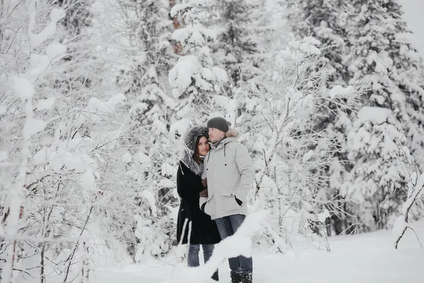 Gyönyörű fiatal európai pár pulóverben télen az erdőben ölelkeznek, csókolóznak. Férfi és nő, utazás, természet. Szerelmes, barátnő. Karácsonyi ünnepek, kikapcsolódás a bázison. — Stock Fotó