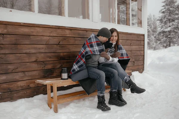 Jeune couple amoureux dans les bois se prélassant sous une couverture. Ils boivent du thé dans un thermos — Photo