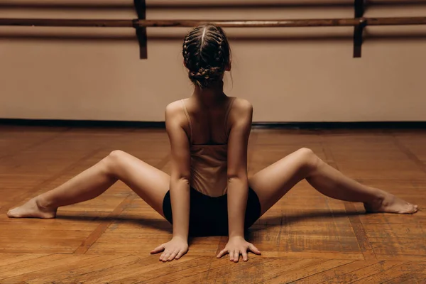 Foto seorang penari muda yang cantik peregangan benang tengah di studio dengan latar belakang barre. — Stok Foto