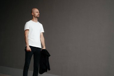 Gri arka planda beyaz tişörtlü yakışıklı kel bir adamın resmi. Yüksek kalite fotoğraf