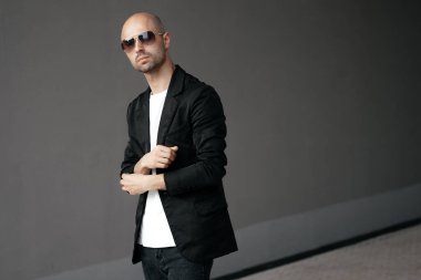 Gri arka planda beyaz tişörtlü yakışıklı kel bir adamın resmi. Yüksek kalite fotoğraf